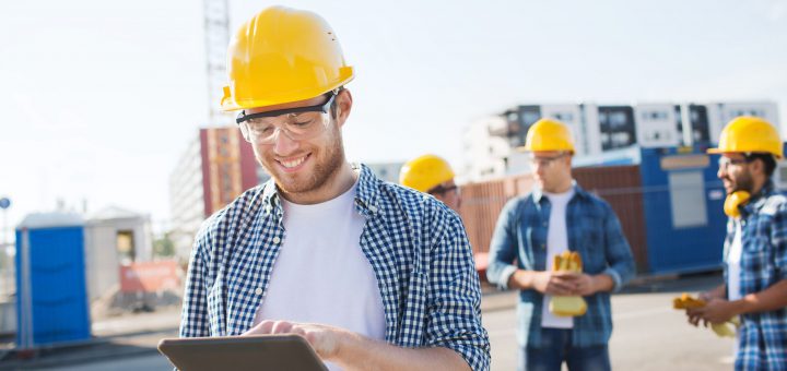 smiling builders in hardhats with tablet pc