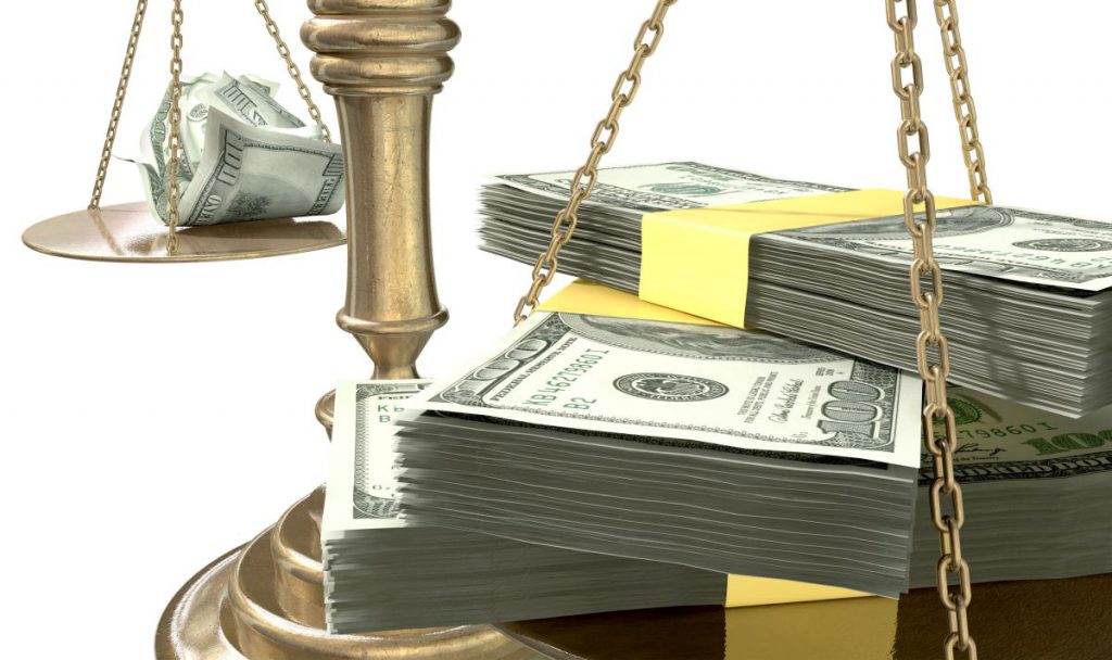 An old school bronze justice scale with stacks of us dollar money on one side and a few crumpled notes on the other representing the inequality in the income gap an isolated white background