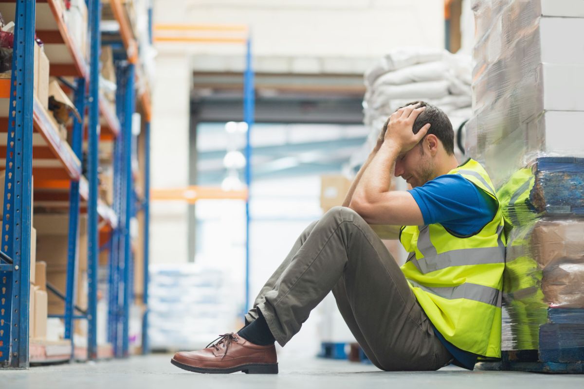 Tired man sitting on the couch with a headache in warehouse