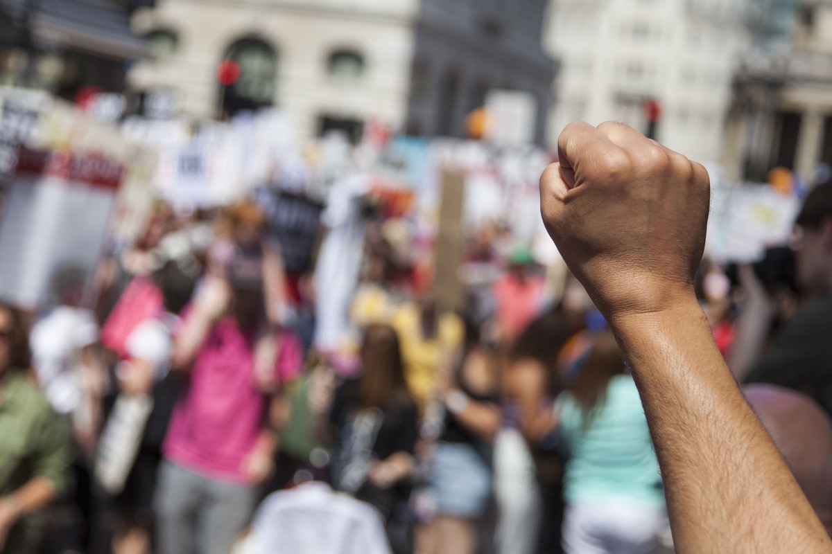 A raised fist of a protestor at a political demonstration representing the Fight for $15 movement