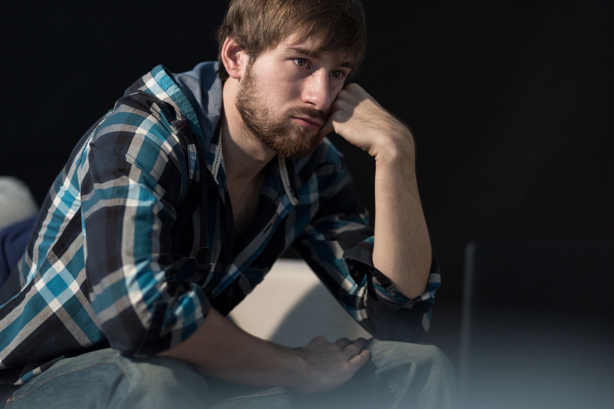 Young unemployed man sitting on the sofa, representing the realities of the unemployment rate