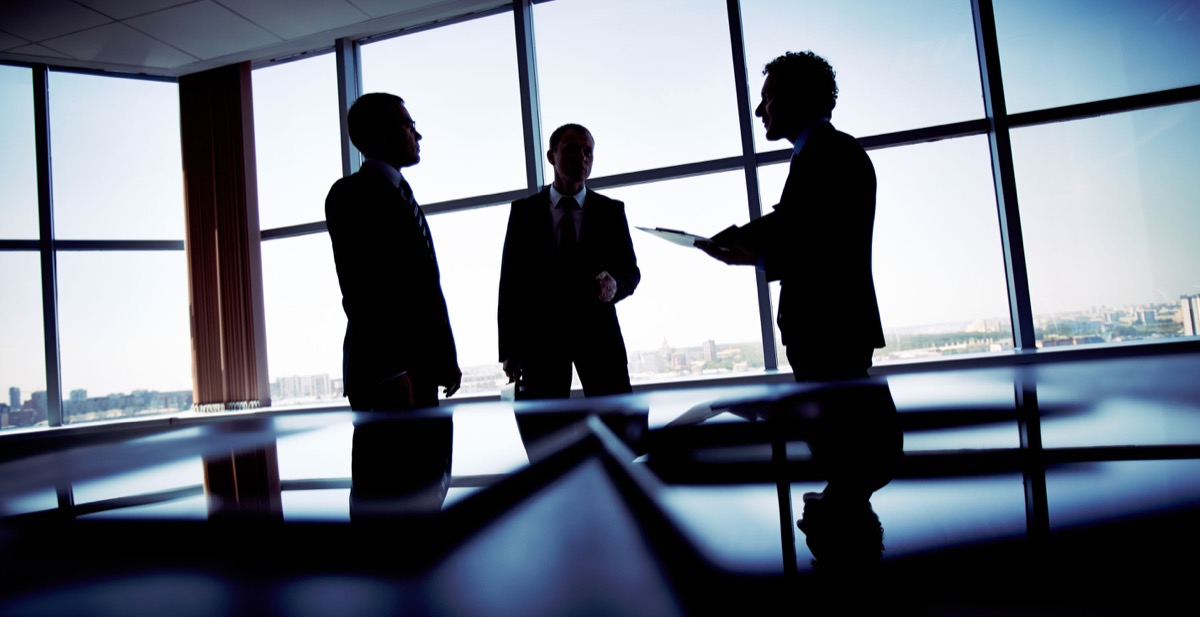 Shady image of a manager discussing business matters with his subordinates - labor wins