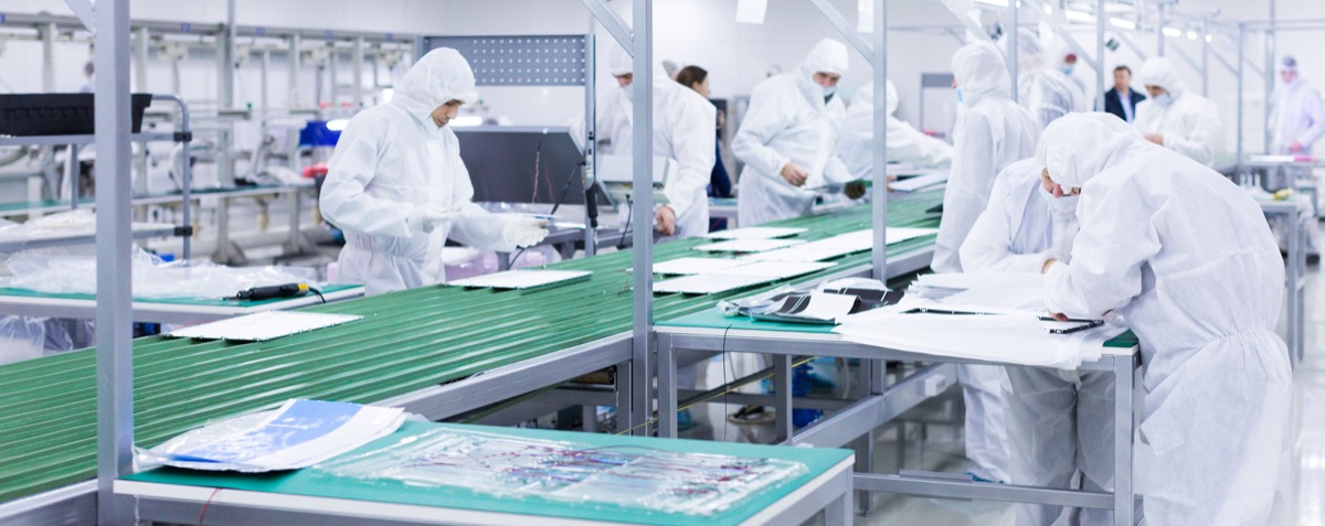 factory workers in white lab suits and face masks; foreign manufacturing concept