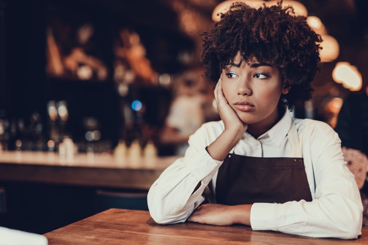 Tired young lady looking aside and sitting over table; need for cost-of-living increases concept