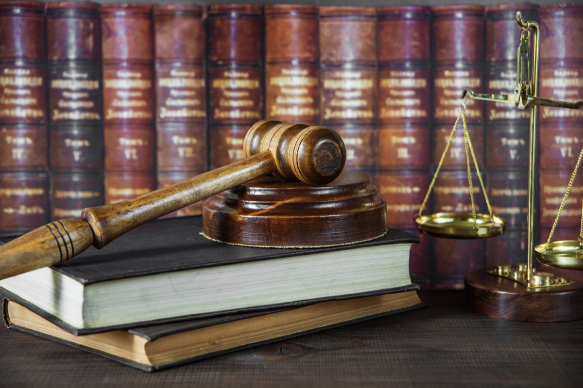 Wood gavel, soundblock, scales and stack of old books against the background of a row of antique books bound in leather; Union informational concept