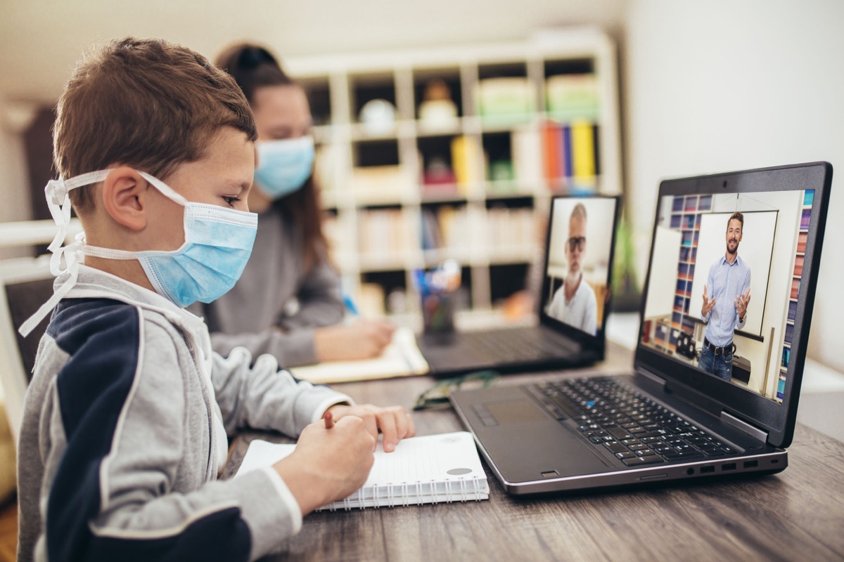 Boy and girl studies at home, wear protective masks, and doing school homework. Distance learning online education. Teachers unions concept