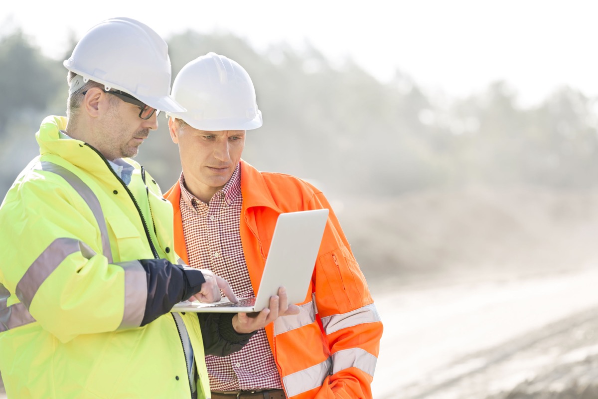 supervisors using laptop at construction site; concept: unions are standing up for workers as they go back to work