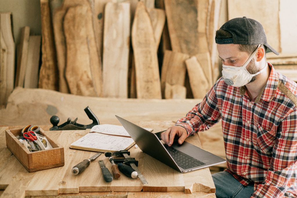 woodworker masked in his shop using a laptop; union meetings during pandemic concept