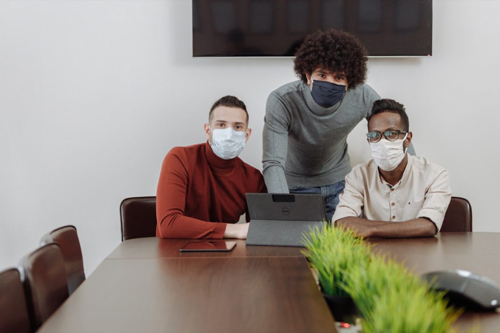 Three masked office workers in a conference room; union meetings during pandemic concept