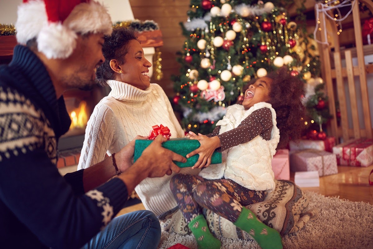 Happy family on Christmas opening gifts sitting on floor at home; buy union-made gifts concept