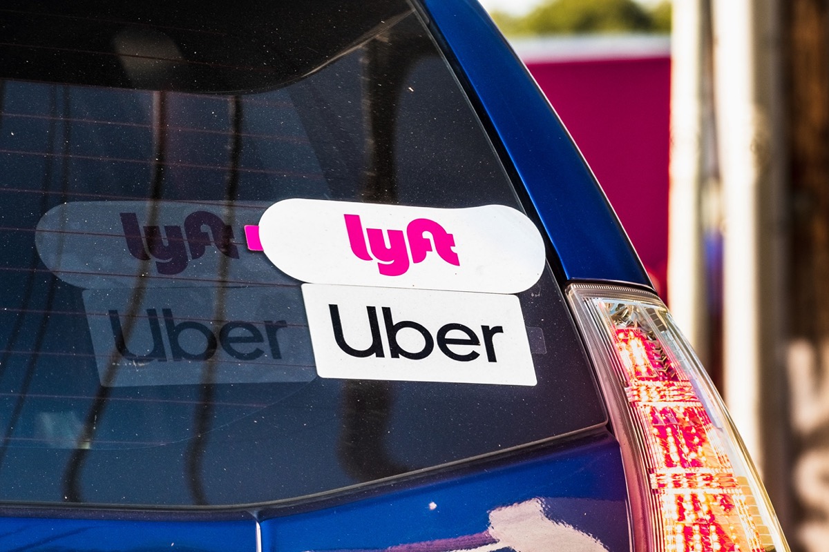 Blue car with Uber and Lyft stickers on back windshield; Prop 22 and American workers concept