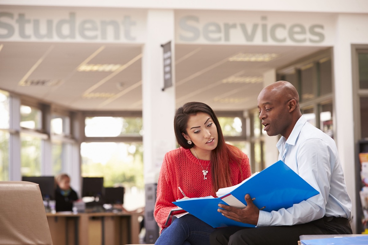 College Student Having Meeting With Tutor To Discuss Work; university workers concept