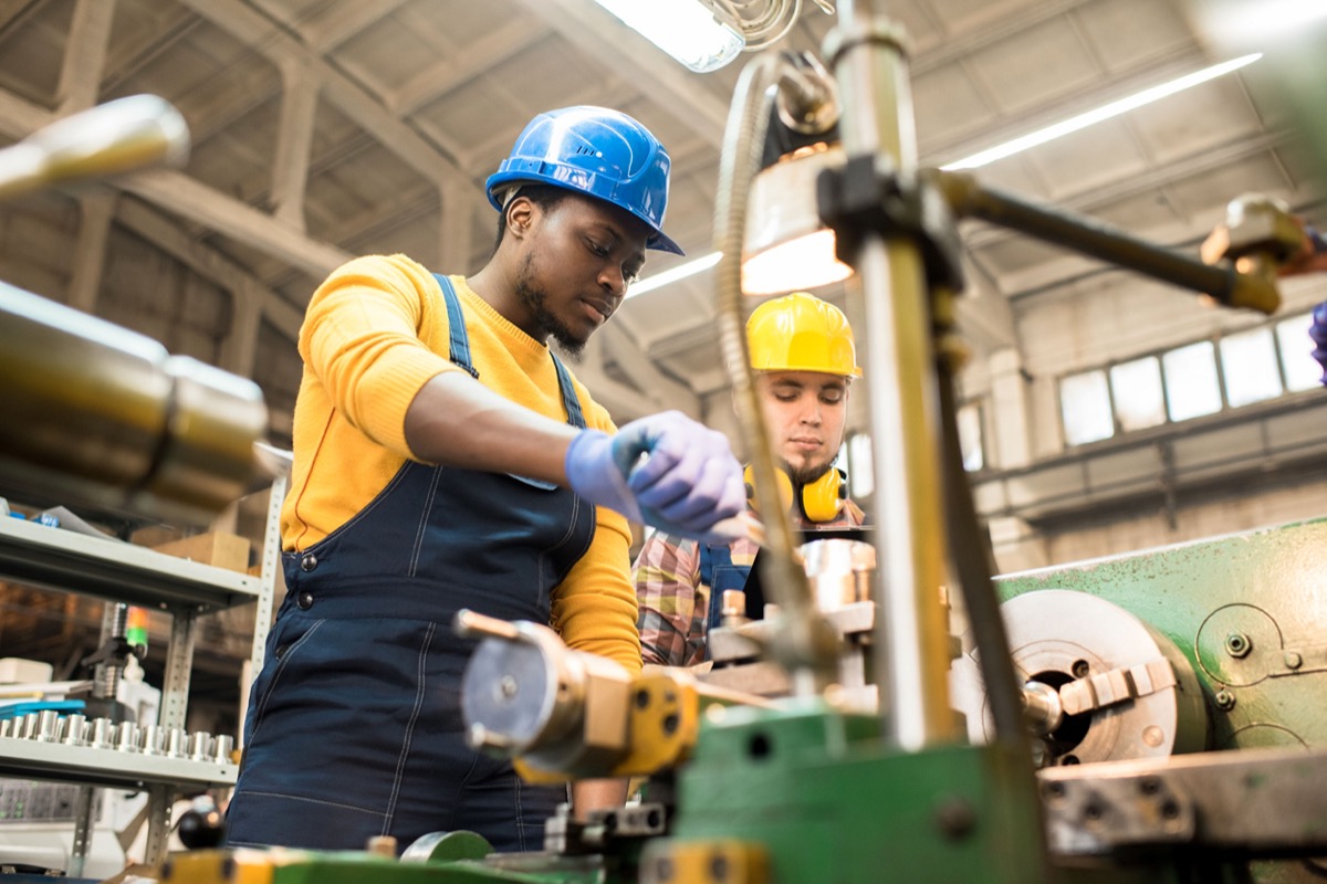 Two workers wearing overalls and protective helmets using lathe; NLRB’s new proposed privacy rule concept