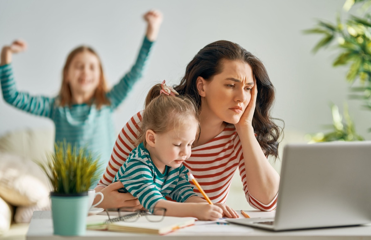 Working mom on a laptop at home caring for two childern