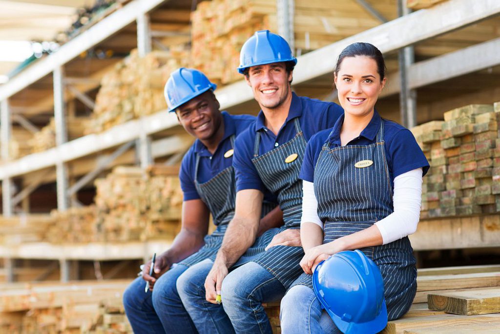 group of cheerful young hardware store co-workers resting at timber yard