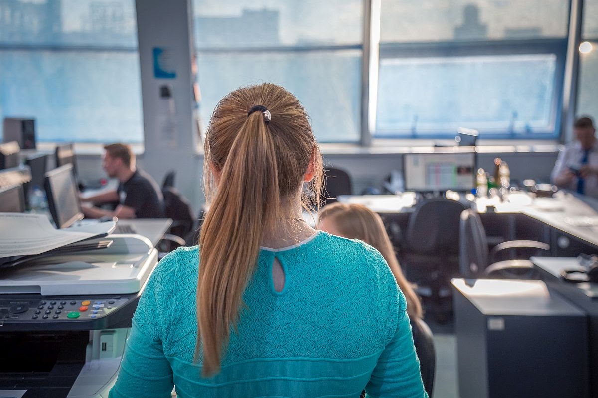 back of the head of an office worker with a pony tail, looking onto a cluttered office; successful union drives concept