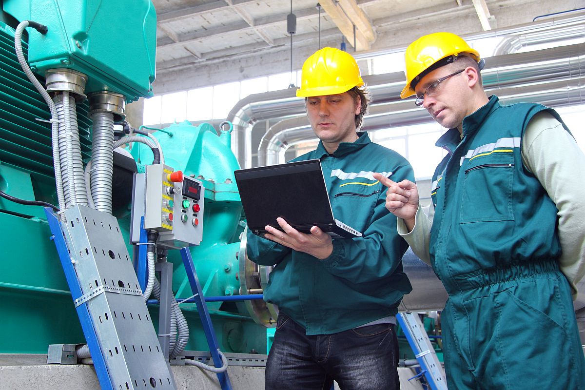 Industrial workers in jumpsuits and yellow hardhats; workplace safety concept