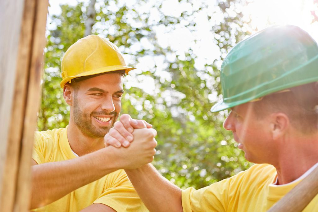 Two workers in hardhats shake hands -- department of labor news