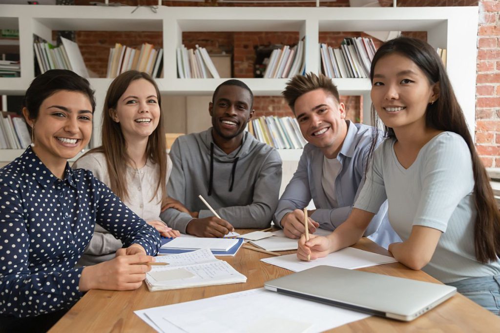 Group of young people sitting around a table with papers and a laptop; white-collar workers concept