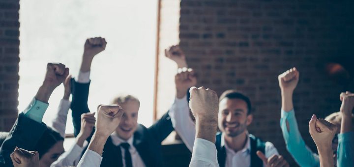 Group of professionals celebrating, with fists in the air; union dues concept