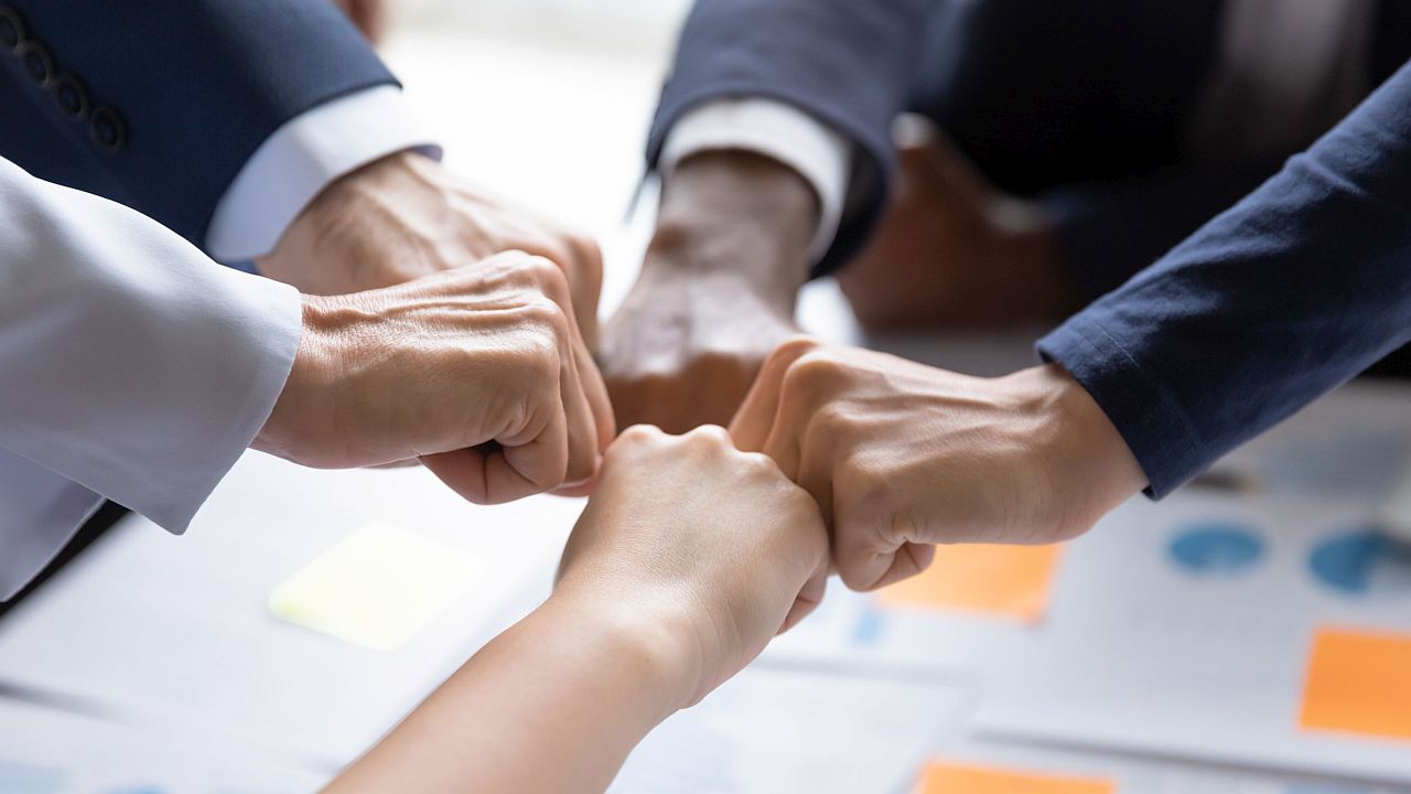 Group of professionals fist bump as a symbol of solidarity; contract negotiations concept
