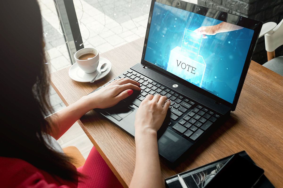 Woman working on lap top which has image of person voting; new union concept