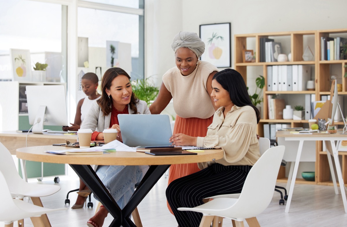 Diverse group of smiling business women using a laptop for a brainstorm meeting in an office; union represent your workplace concept.
