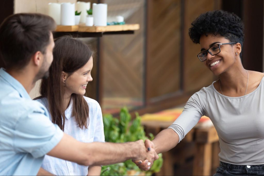 Smiling people at cafe shaking hands; union organizer concept