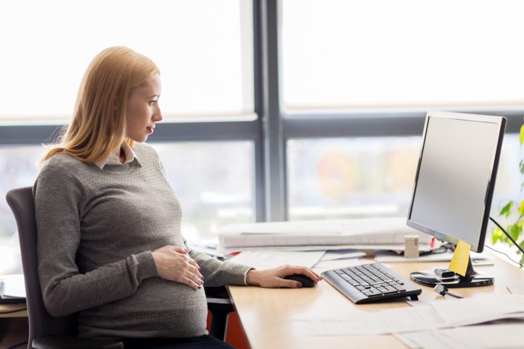 Pregnant woman sitting at her desk in the office; DOL initiatives concept