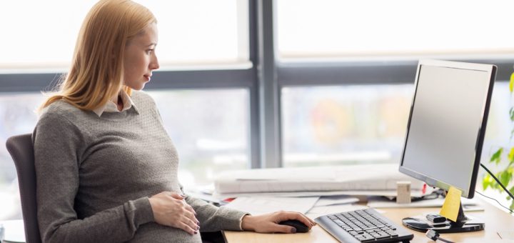 Pregnant woman sitting at her desk in the office; DOL initiatives concept