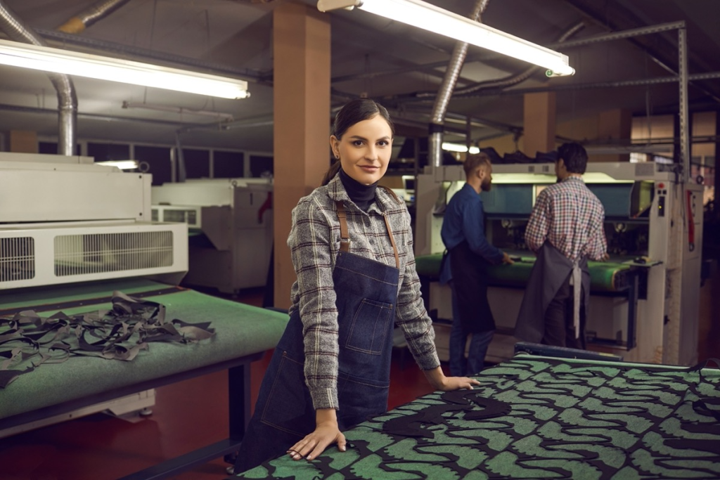 female worker in machine shop smiling; Fair Contracts concept