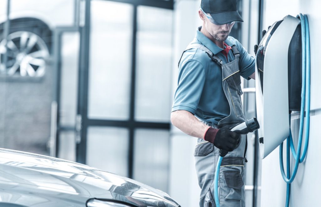 Automotive technician testing wall charger for EV vehicles; Inflation Reduction Act benefits concept