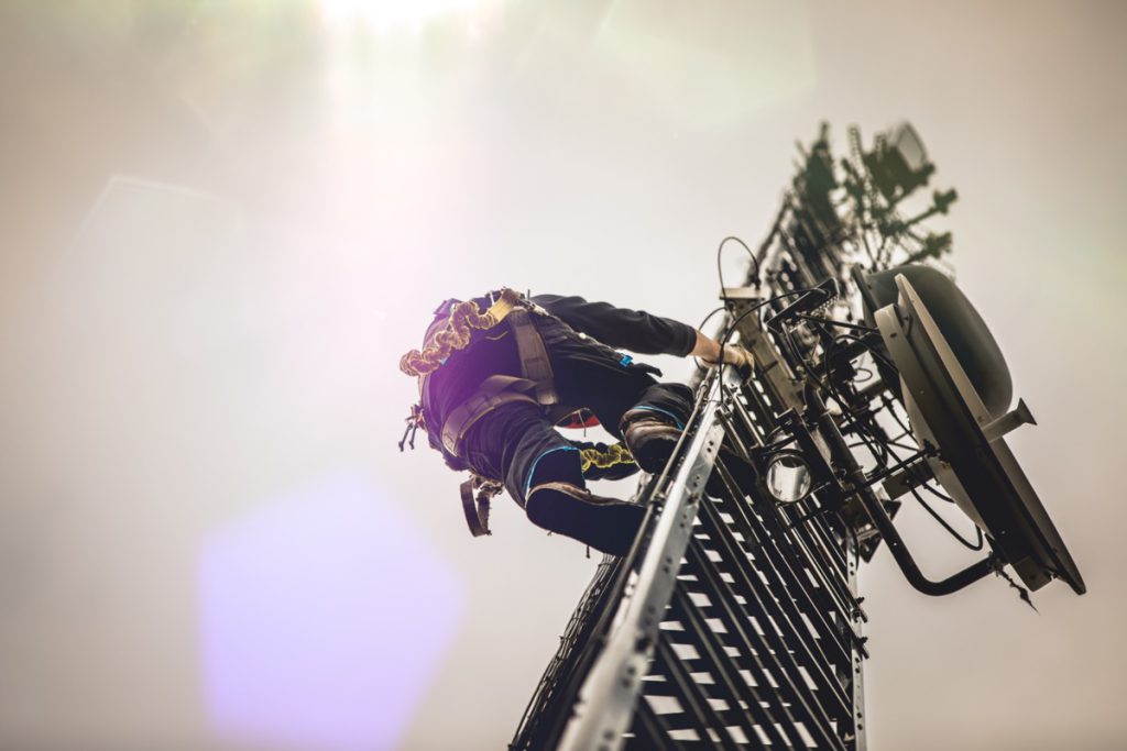 Telecom worker climbing antenna tower; safer working conditions concept